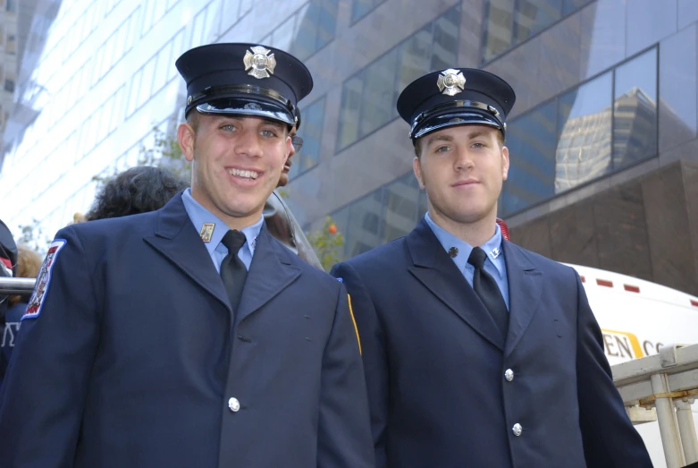 two men in blue jackets are smiling at the camera