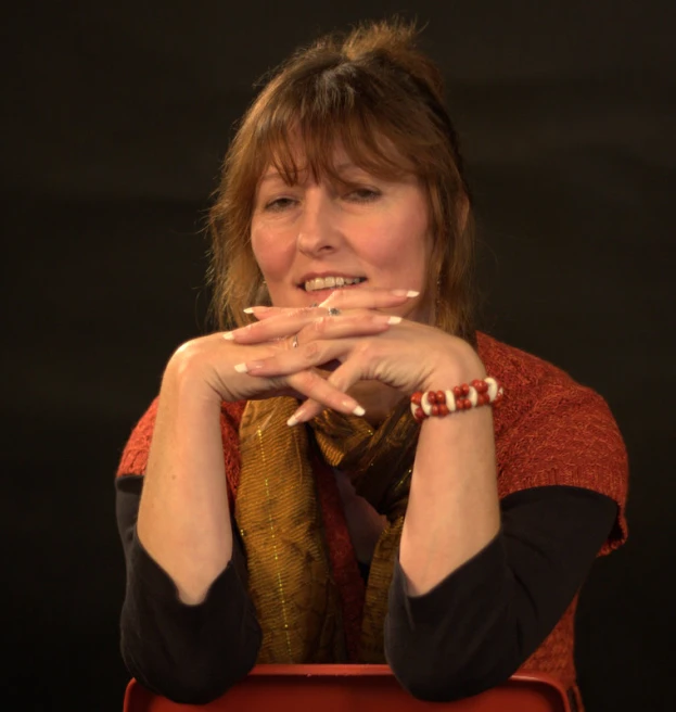 woman sitting in a chair while holding her hands on her chest