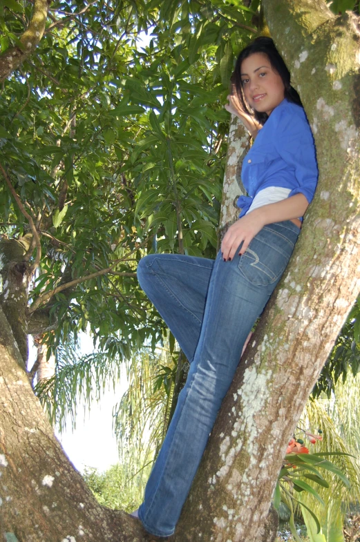 a woman sits in a tree with her legs hanging out