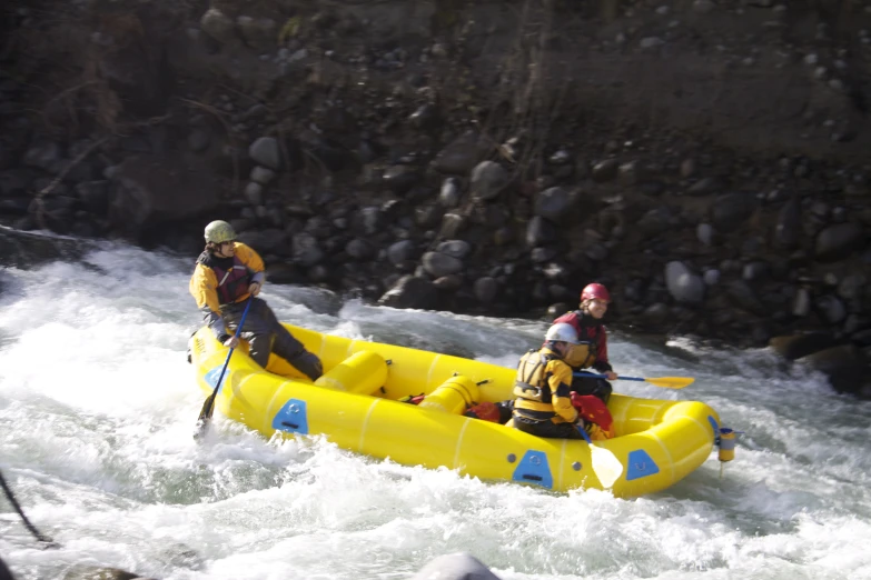 people riding on rafts in rapids near rocky area