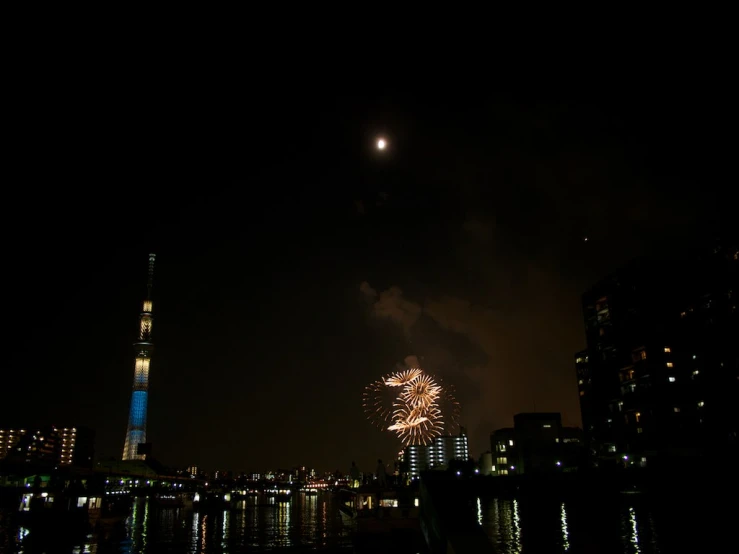 a bright fireworks in a dark sky next to tall buildings
