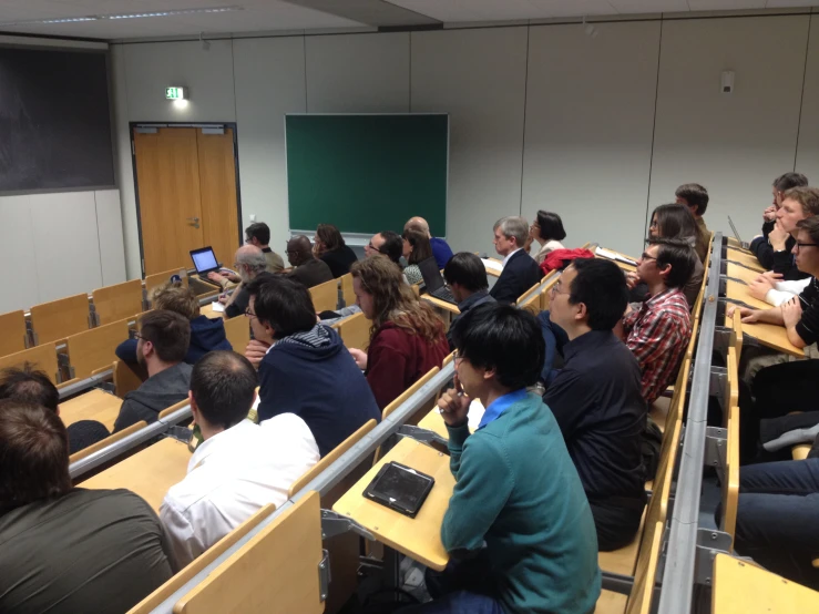 many people sit in rows in front of their laptops and computers