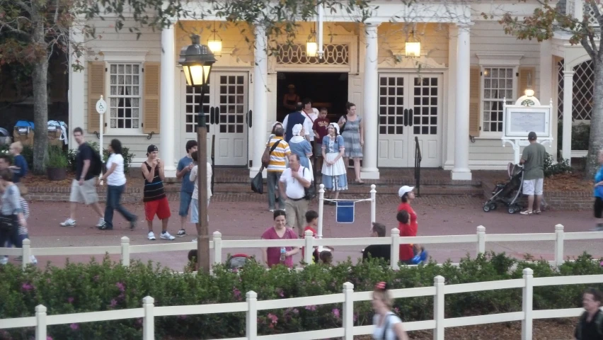 people walking in front of a white house and with flags