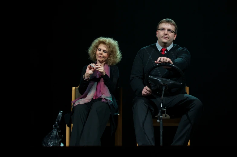 two people are sitting and one is holding a radio