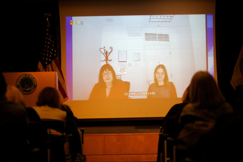 a video on a projector that includes two women and a trophy