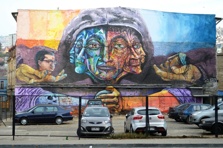 a wall with a colorful painting of different faces