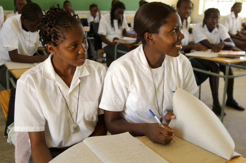 two women in a class room writing and talking