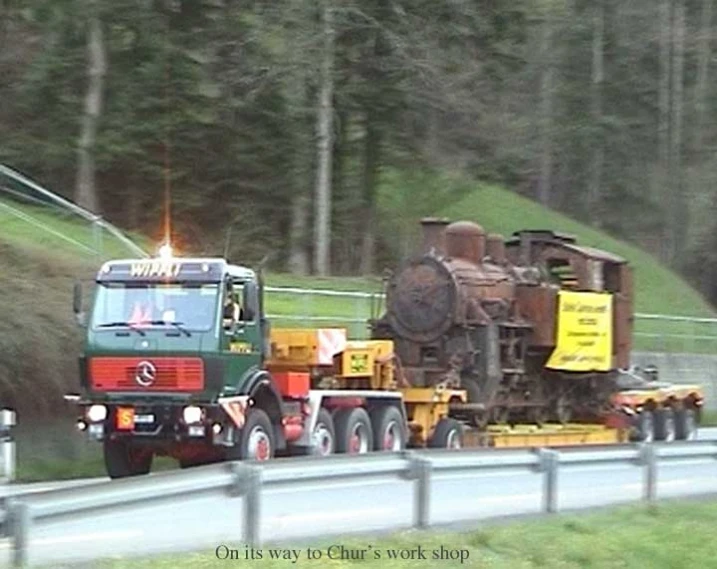 a truck towing a tractor hauling a large truck down a mountain road