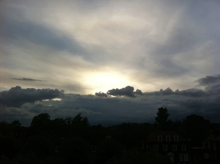 sun setting behind storm clouds over homes