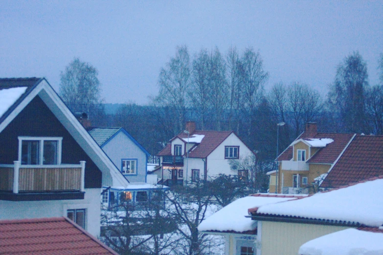 the roof tops of homes with snow falling down