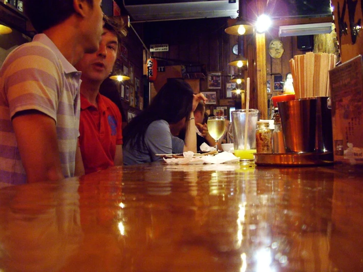 three people sitting at a bar eating and drinking