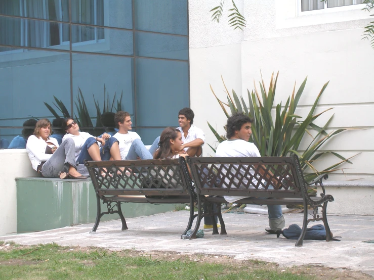 some s are sitting on a bench in front of a building