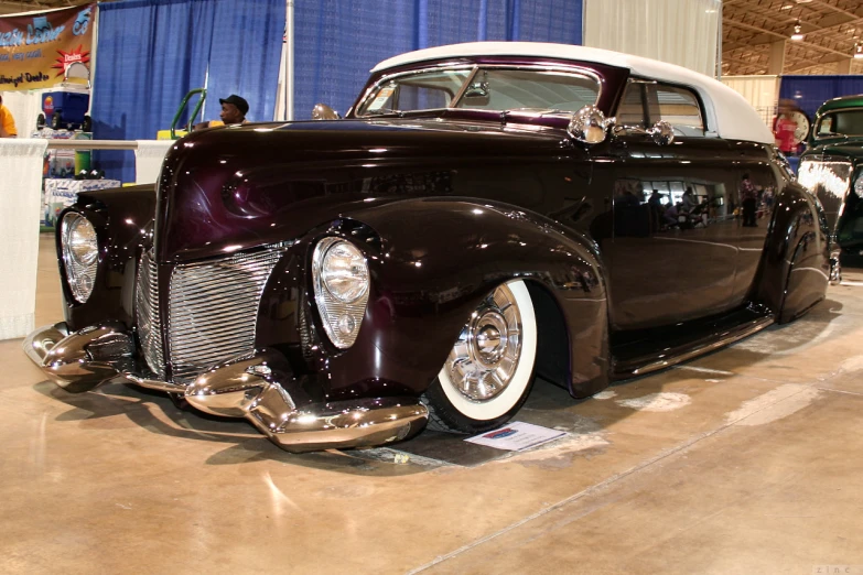 an old classic car on display with other cars nearby