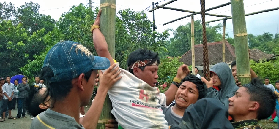 some s are standing around while a man is fixing soing on a pole