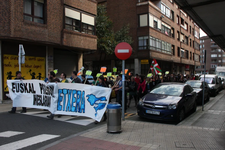 people protesting outside in front of a building with a car parked in the lot