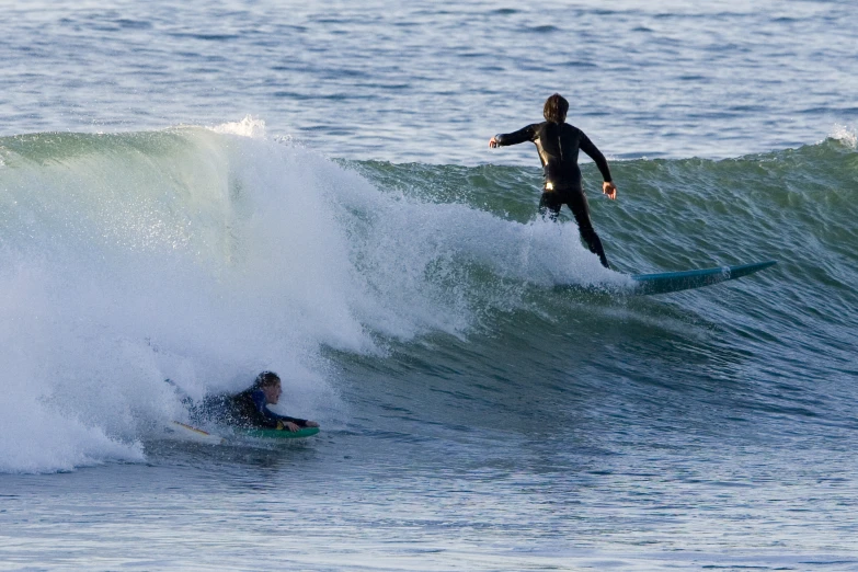 two surfers in wetsuits riding big waves