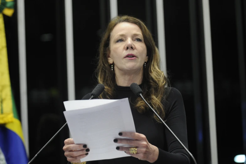 woman in black shirt speaking from a lectern at an event