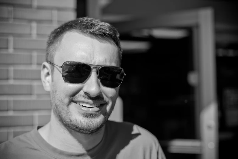 a smiling man in sunglasses looks into the camera