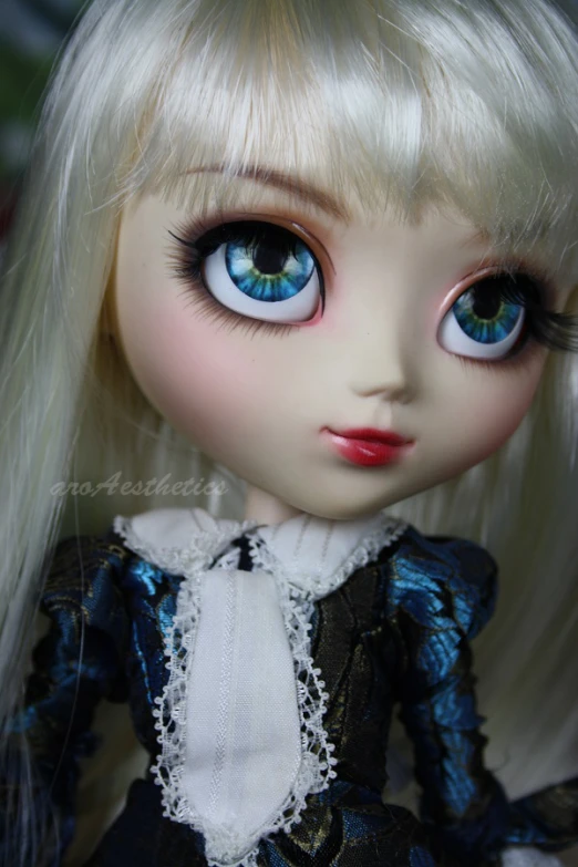 closeup of white doll with blue eyes, white dress, and long blonde hair