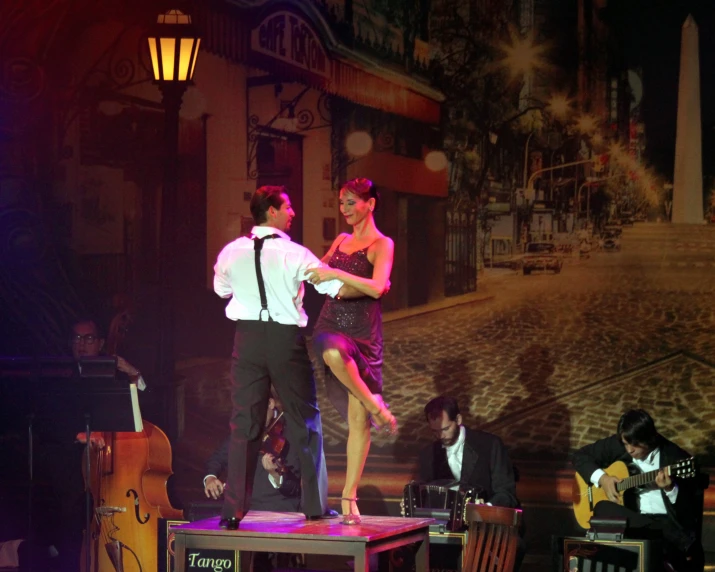 a couple is dancing on a platform with instruments