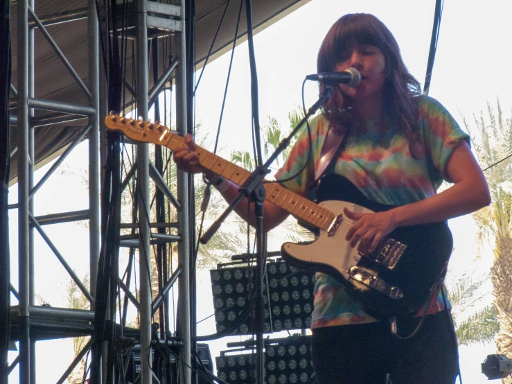 a man in tie dye shirt playing an electric guitar