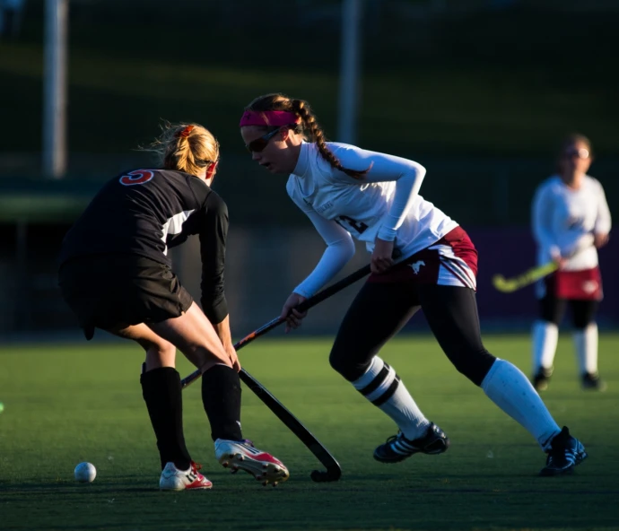 two women playing a game of hockey on a field