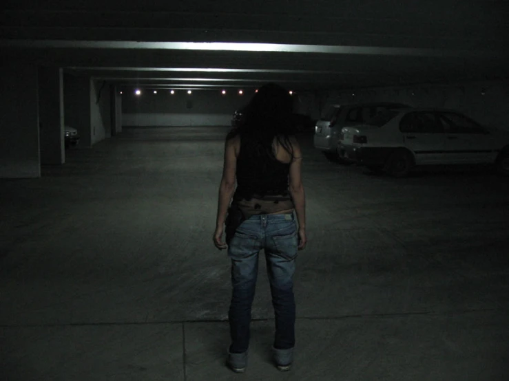 a woman stands in the middle of an empty parking garage