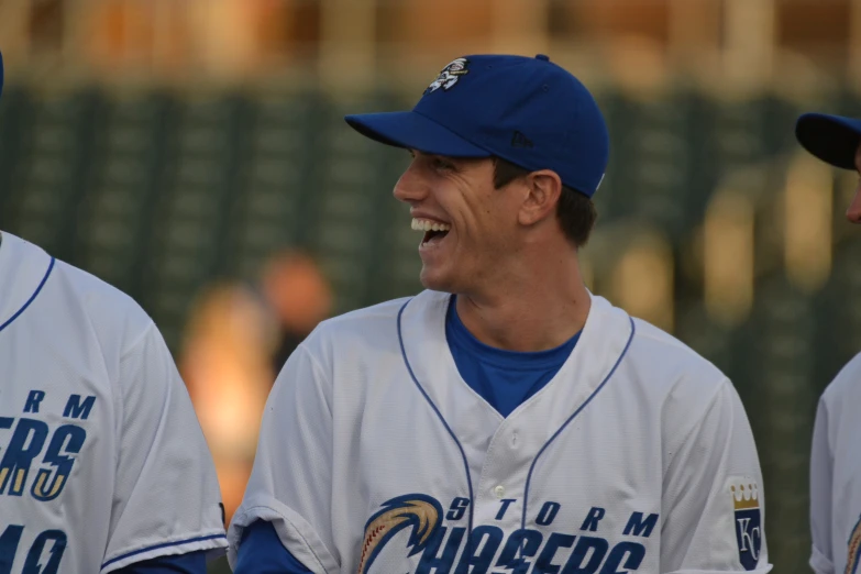 two baseball players are laughing together with one of them on the side