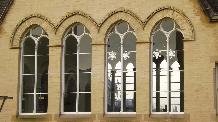 an old yellow brick building has three large windows and a clock tower