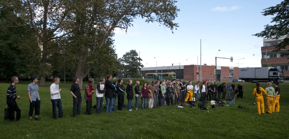 people standing in a long line outside with trees behind them