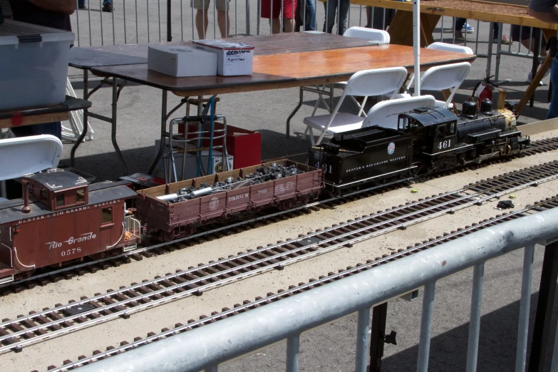 a bunch of people are standing around a model train