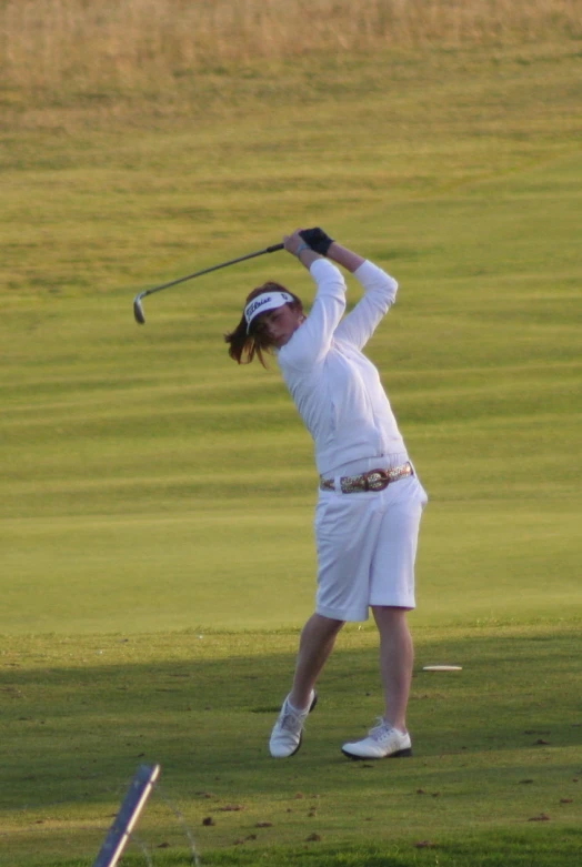 a person swinging a golf club on a field