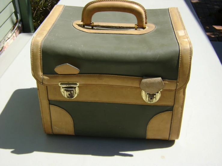 a tan and black suitcase with handles is sitting on a bench
