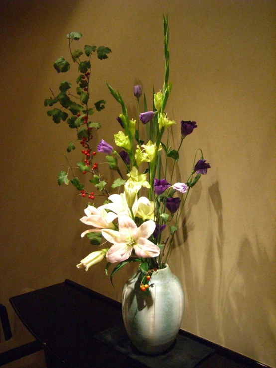 a vase of flowers on a table with a wall in the background