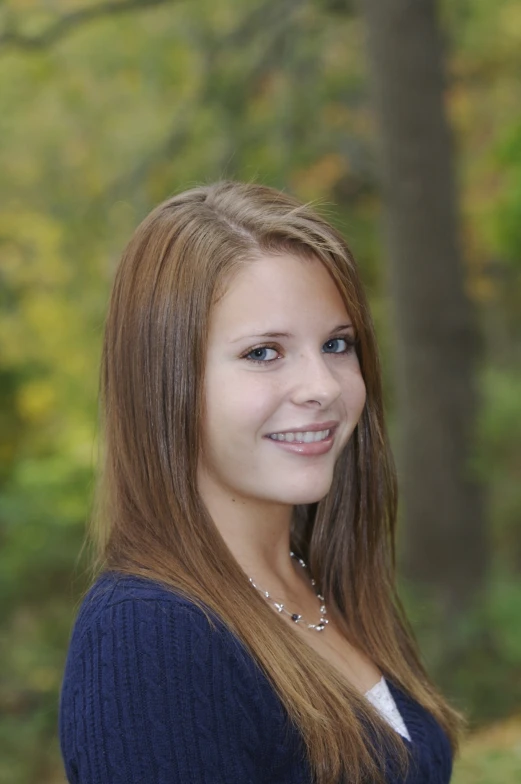 a young woman posing for a po in front of trees