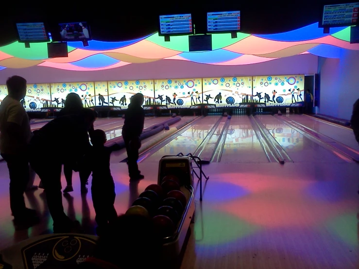 several people at a bowling alley with brightly colored lights