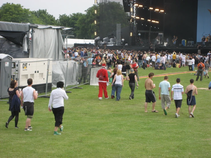 a group of people walk through the grass towards the stage