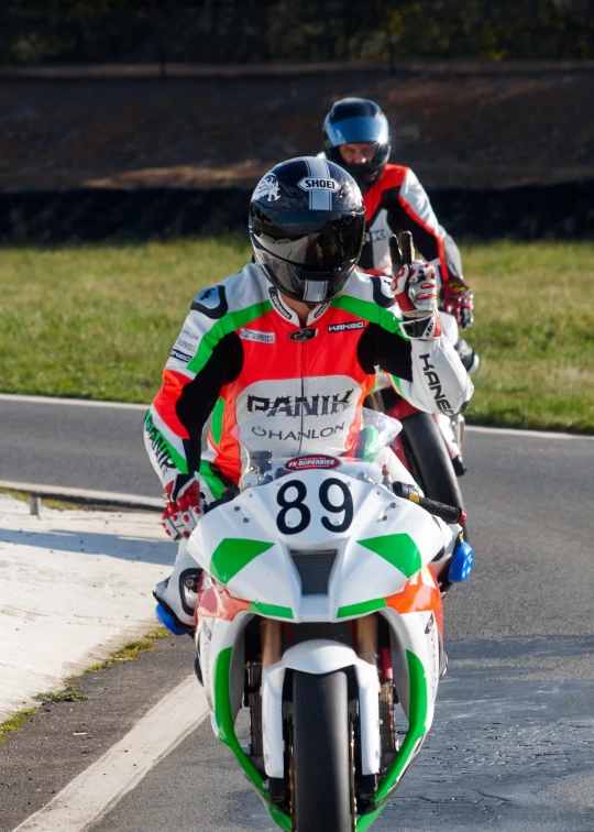 two men wearing helmets on motorbikes on a track