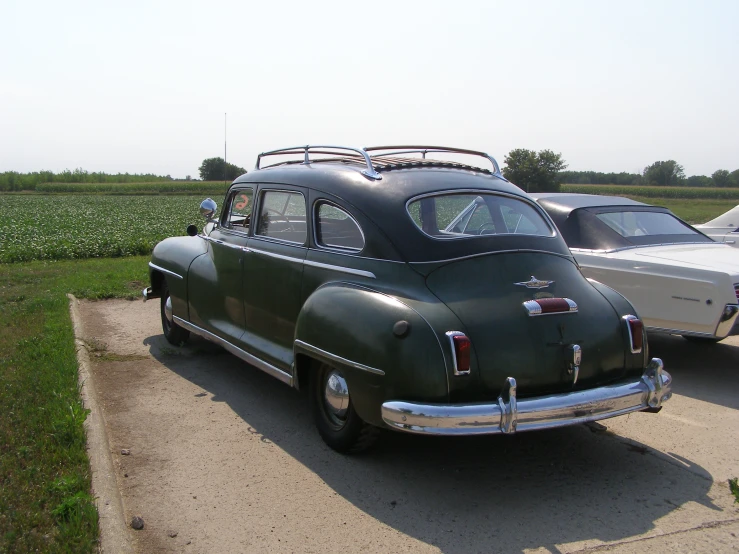 an old car parked in front of an older style boat