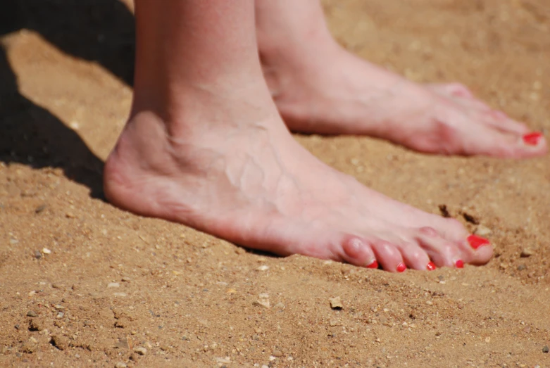 two red toenails are pictured on top of the sand