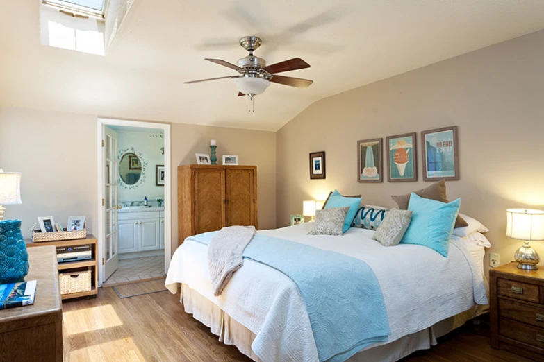 a room with a bed, two nightstands and a ceiling fan