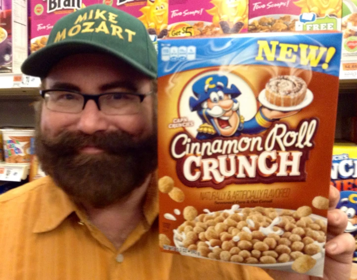 a man wearing a green hat holding up a box of cereal