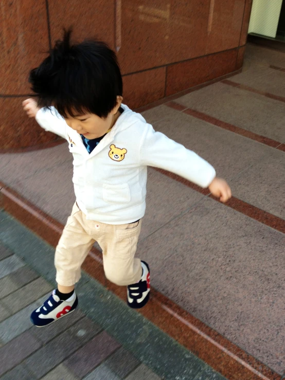 young child on skateboard outside in front of brick building