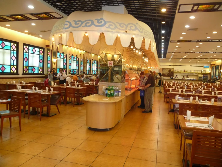 people sitting at tables in a restaurant with windows above them