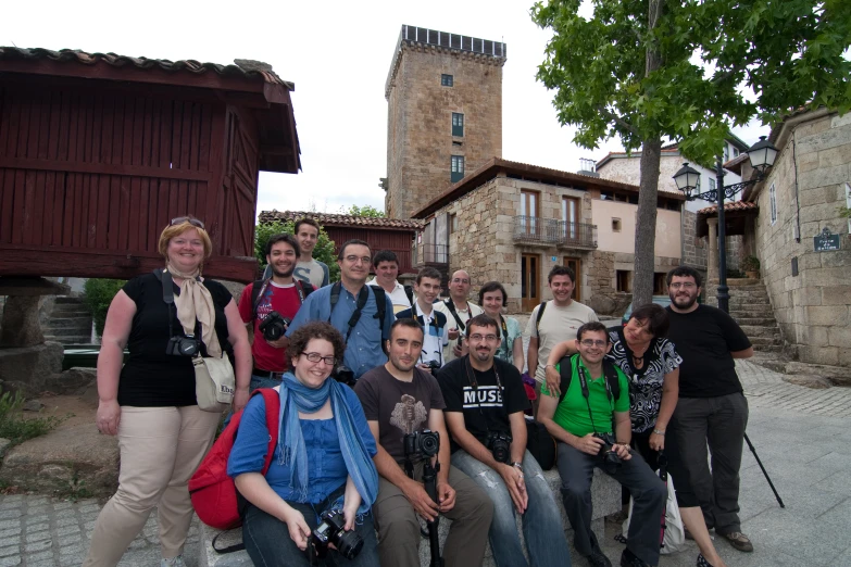 a group of people sitting next to each other in front of buildings