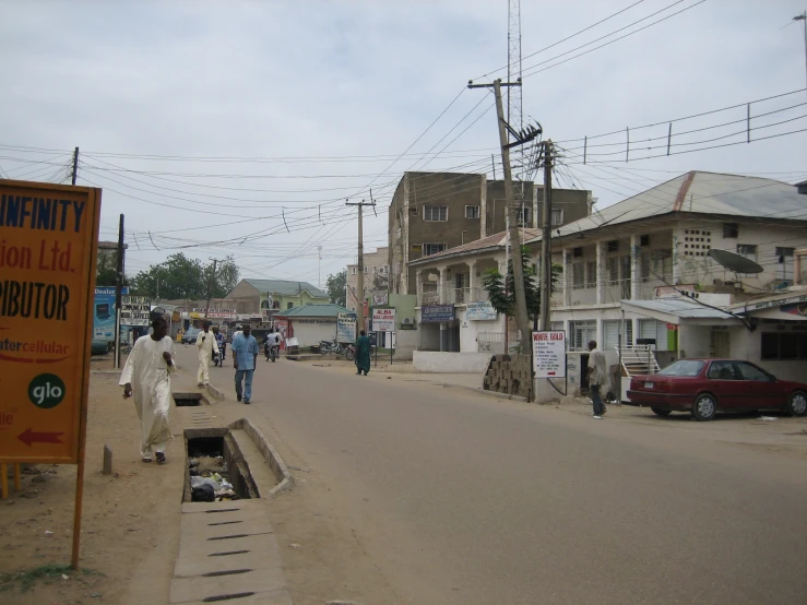 a group of people walk down the street near houses