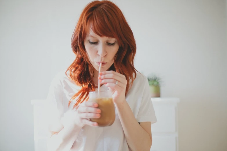 an attractive woman drinking a drink from a glass