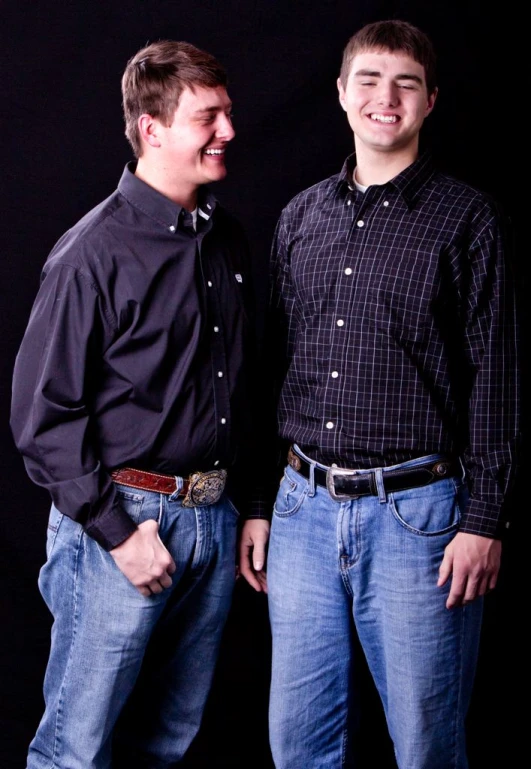 two guys wearing jeans and shirts posing for a picture