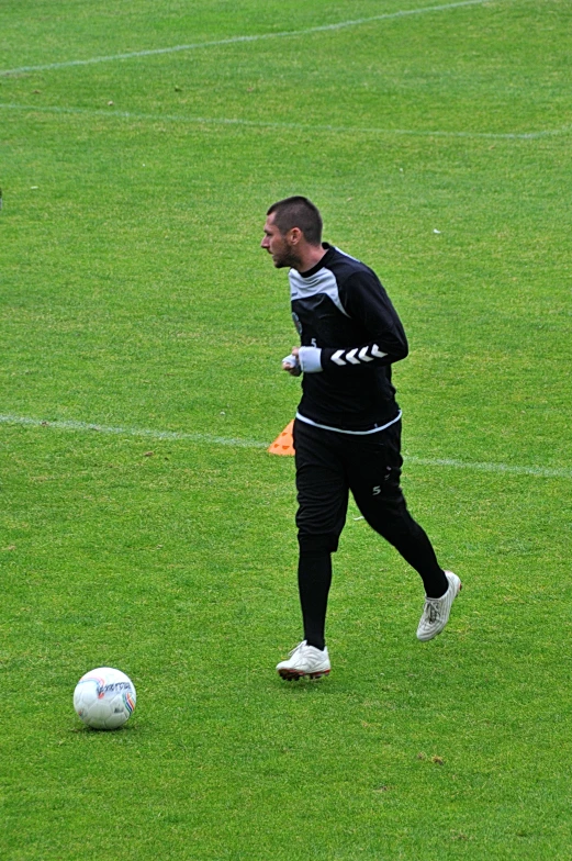 a man standing on top of a lush green field near a soccer ball