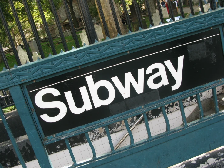 a subway sign on a fence by a building